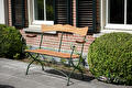 Houten tuinbank met groen smeedijzeren frame voor bakstenen gevel