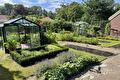 Zonnige tuin met kas, buxusvakken, lavendel en moestuinbedden