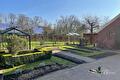 Aangeharkte moestuinbedden met buxushagen en tuinkassen in de zon