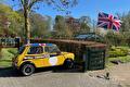 Gele Mini Cooper op het erf met Britse vlag erboven