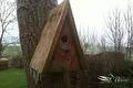 Houten vogelhuisje aan een boomstam met ijspegels