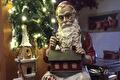 Kerstmanbeeld met huisje naast verlichte kerstboom en houten kerkje