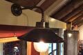 Wandlamp met donkere metalen kap en glazen bol aan een houten wand
