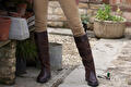 Benen in beige broek met bruine leren Dubarry laarzen op een terras