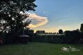 Avondlucht met lichtgevende wolk boven gazon, hagen en bomen