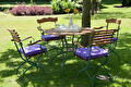 Tuintafel met klapstoelen en paarse kussens op het gazon