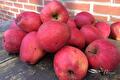 Stapel rode appels op houten ondergrond voor bakstenen muur