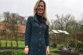Vrouw in lang groenblauw merino vest in de tuin bij de kas