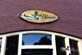 Ovaal houten naambord met eend op bakstenen gevel boven ramen
