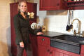 Vrouw in donkergroen tweed colbert in een rode boerenkeuken