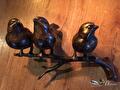 Drie bronzen musjes naast elkaar op een tak