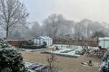 Wit berijpte tuin met tuinkassen in de winterse mist