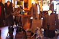 Paspoppen in tweed en wax kleding tussen laarzen en lampen