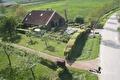 Luchtfoto van een boerderij met tuin, kas en weg