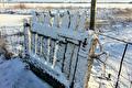 Wit houten hek bedekt met sneeuw voor besneeuwde velden