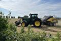 Groene tractor met balenpers op een gemaaid veld