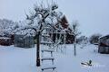Besneeuwde tuin met fruitboom, tuinkas en boerderij